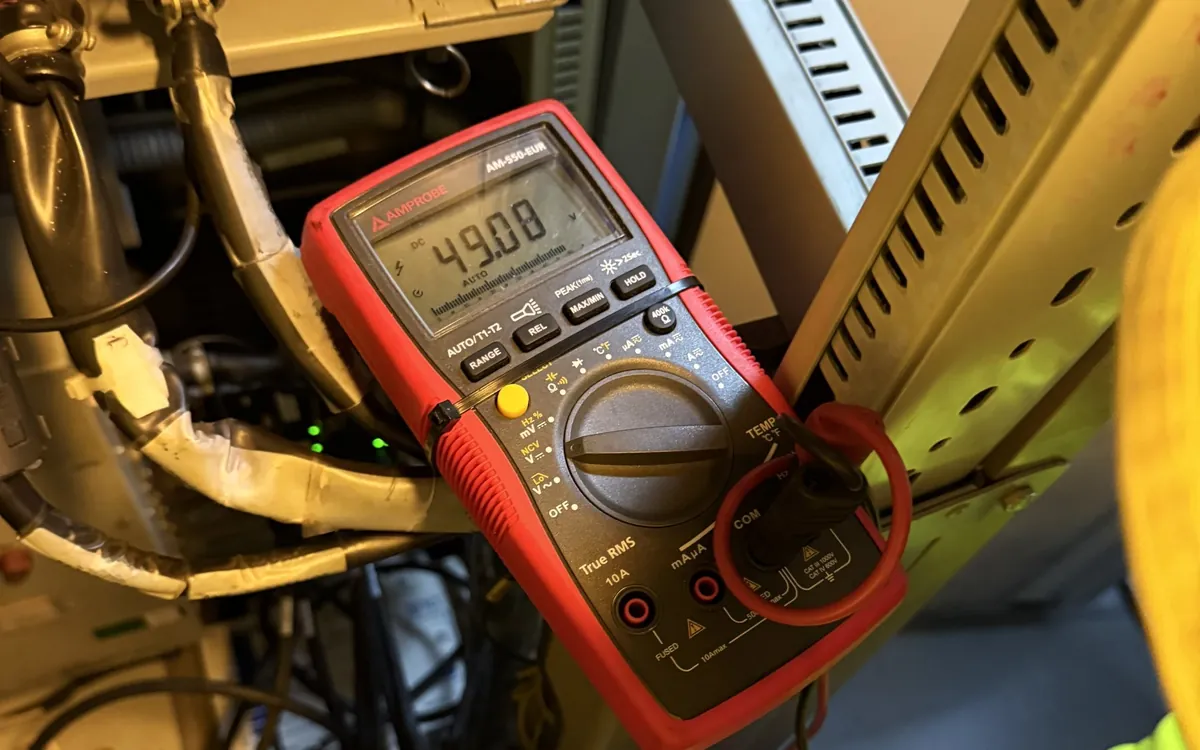 Multimeter taking a measurement in an equipment cabinet